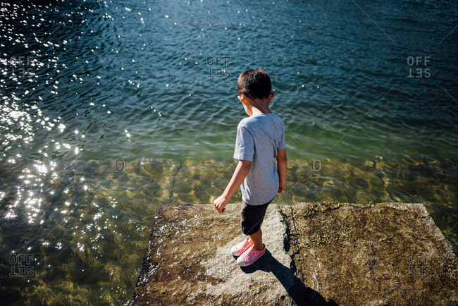 Boy standing on rock as tide comes in