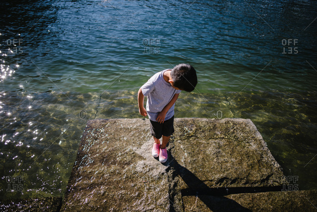 Boy standing on rock as tide comes in