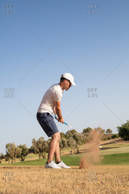 A man hitting golf ball with dust impact