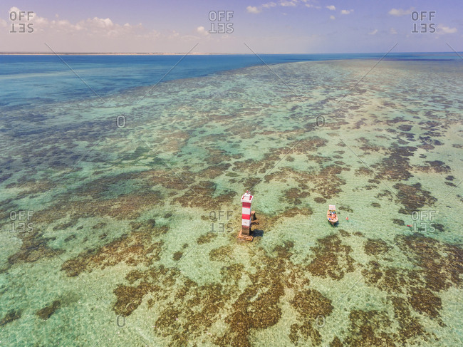 Aerial view of a lighthouse and boat in the clear sea of Rio do Fogo in Brazil.
