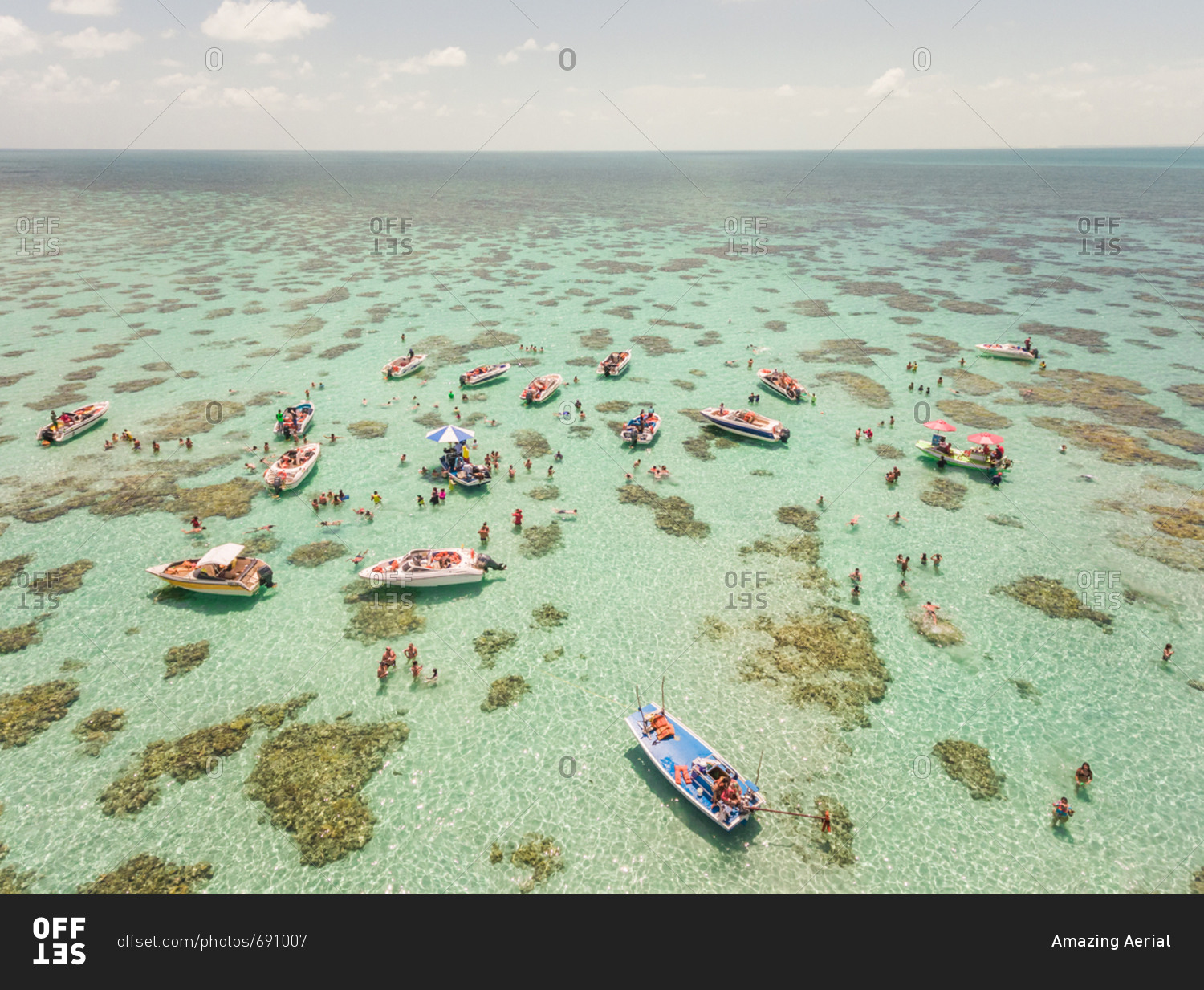Aerial view of boats and people swimming in turquoise sea of Rio do Fogo, Brazil.