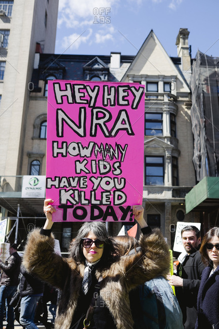 New York, NY - March 24, 2018: Middle-aged woman holding neon gun control protest sign at social activist rally