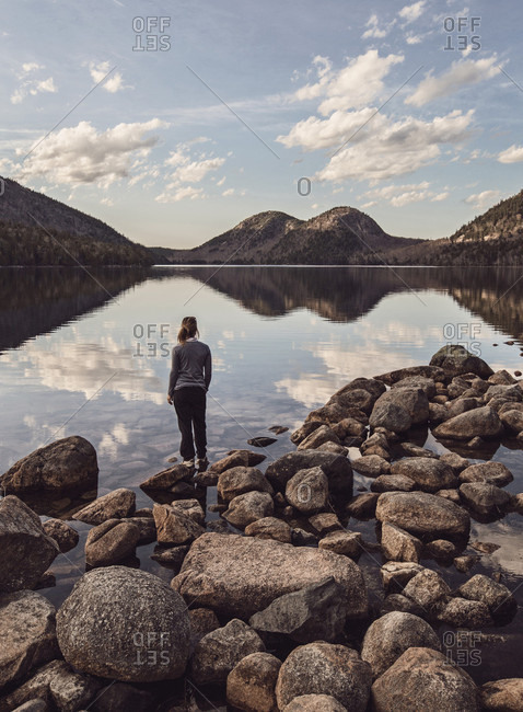 A female hiker stands at the shore of Jordan Pond in Maine's Acadia National Park.