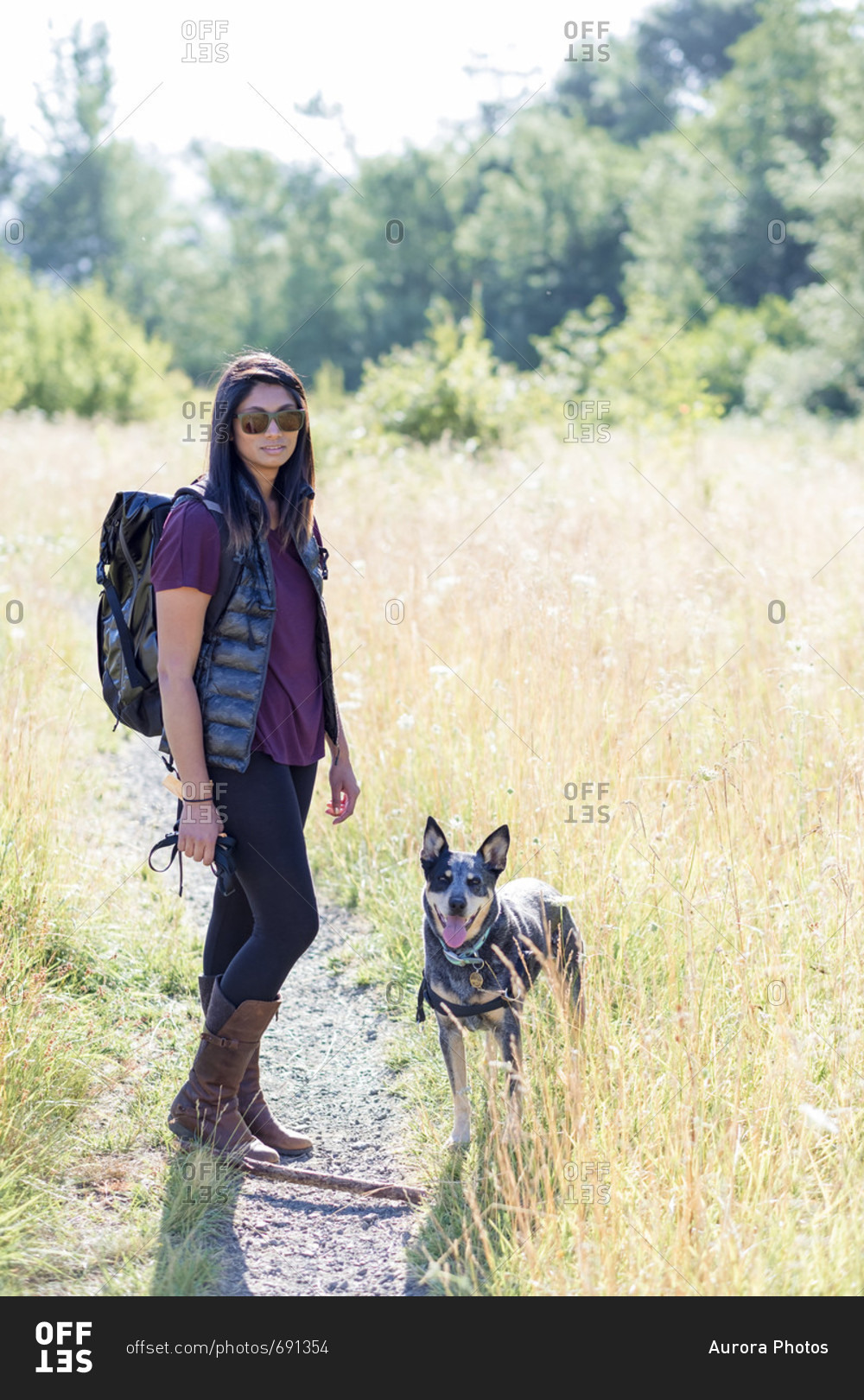 Lifestyle portrait of woman with black backpack on hike with her Blue Heeler dog at Mount Pisgah near Eugene, Oregon, USA