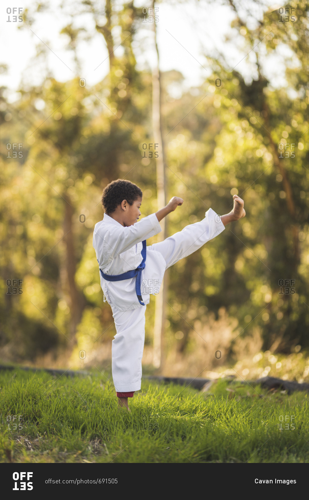 Side view of boy practicing karate on grassy field at park