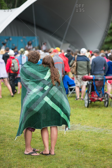 A couple wrapped in a blanket listening to music