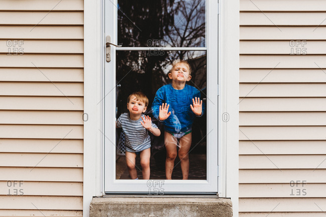 Lips Against The Glass.Two Boys Standing Inside Pressing Lips And Nose Against Glass Door Stock Photo Offset