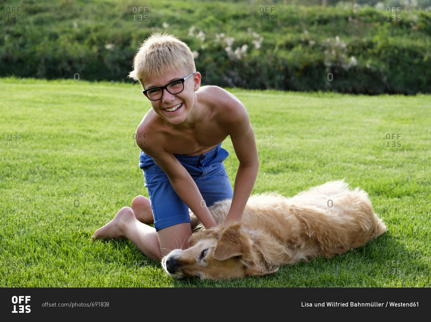 Happy teenage boy playing with dog in grass
