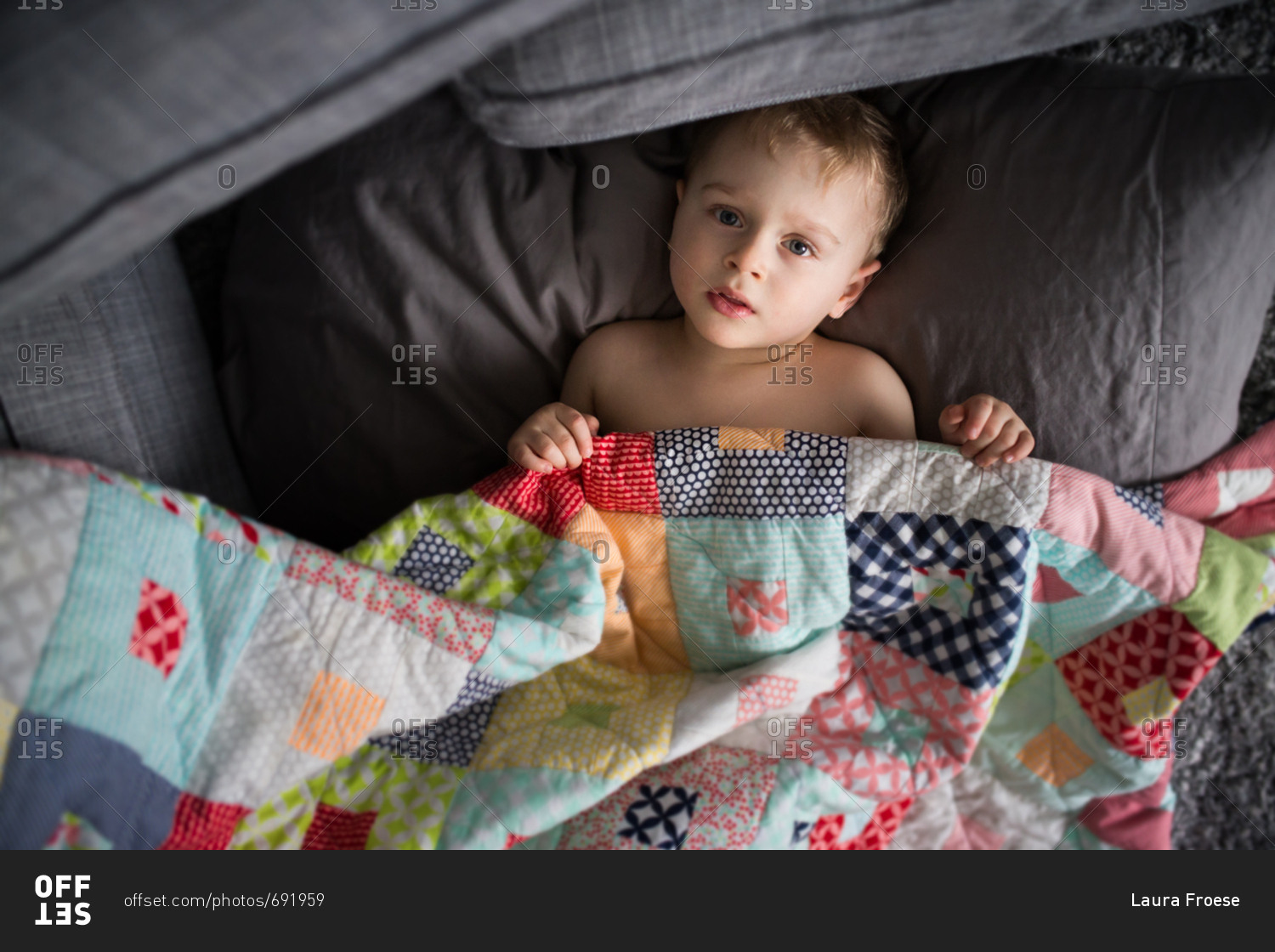 Overhead boy of toddler boy lying on couch with a quilt stock photo