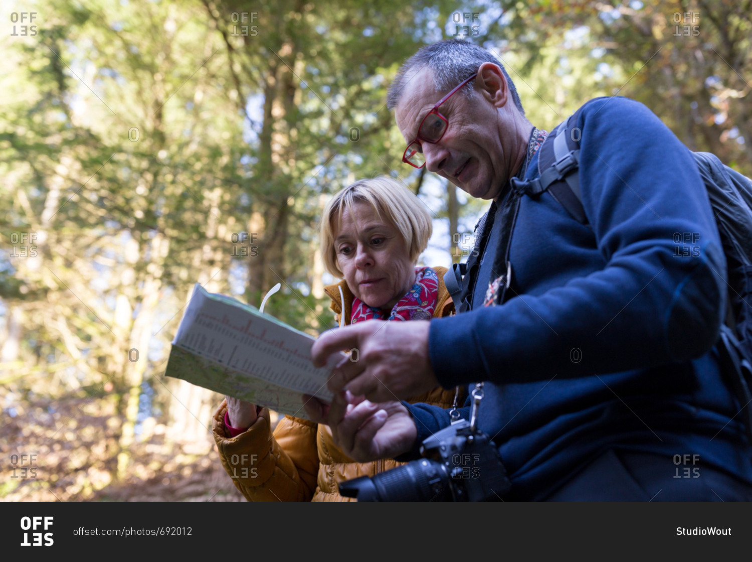Senior couple looking at map in the woods during fall