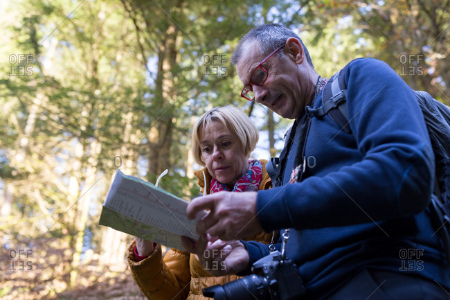 Senior couple looking at map in the woods during fall