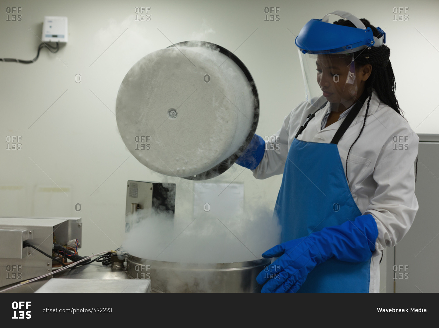 Female scientist opening lid of machine in lab