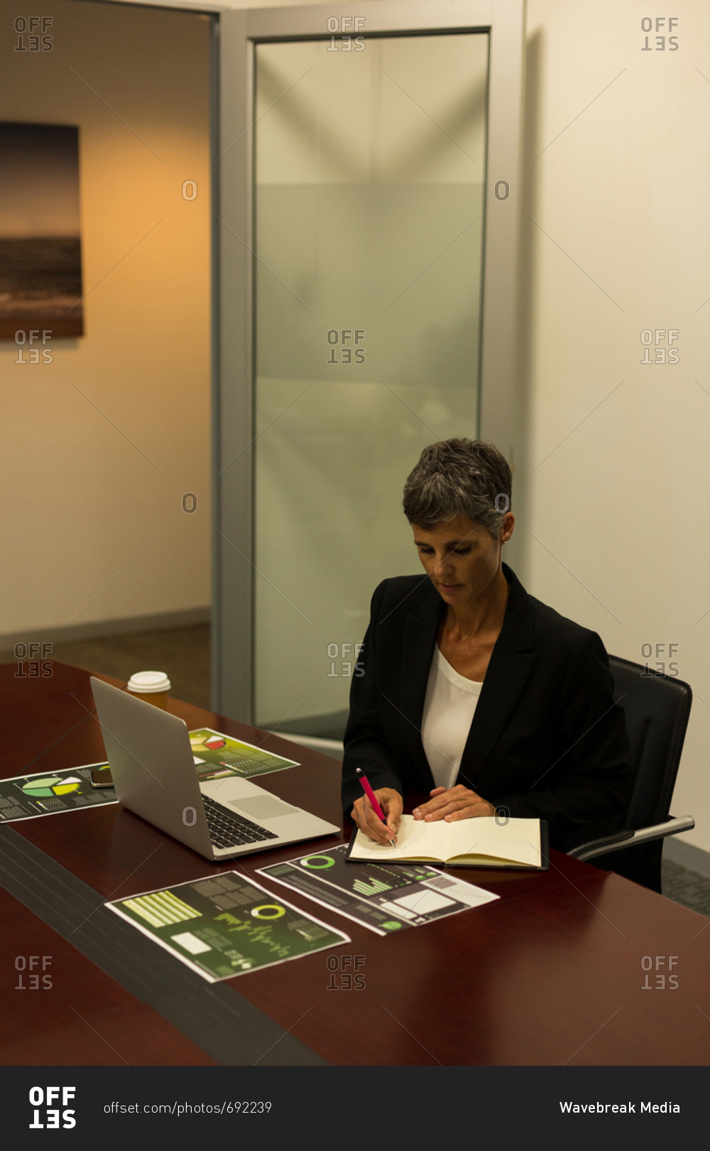 Mature Businesswoman Writing In Diary At Office Desk Stock Photo