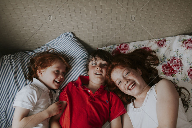 Happy siblings lying on bed together