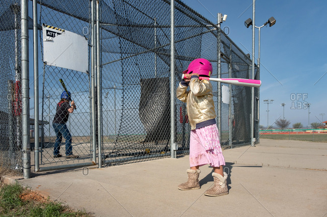 Little girl holding baseball bat at batting cages