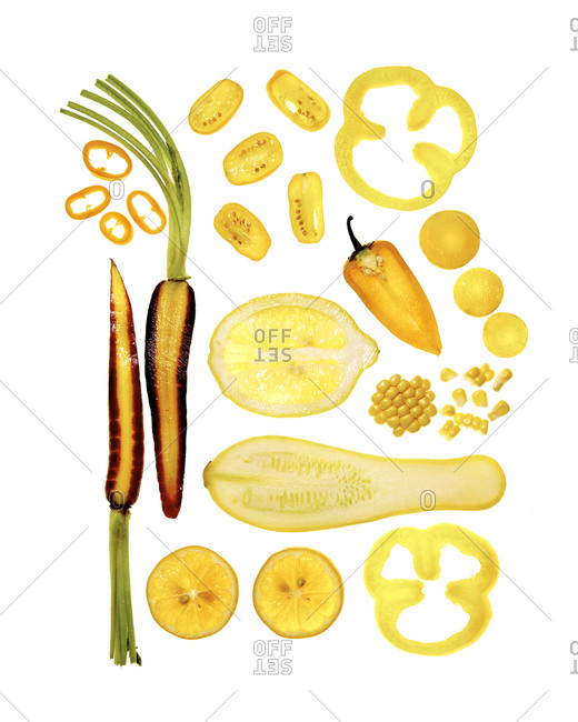 Top down view of artfully arranged sliced yellow and orange fruits and vegetables