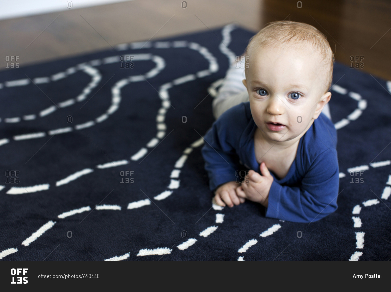 Baby boy trying to crawl on his nursery rug stock photo OFFSET