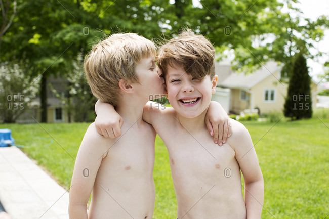 Two shirtless, happy kids embracing outside stock photo - OFFSET