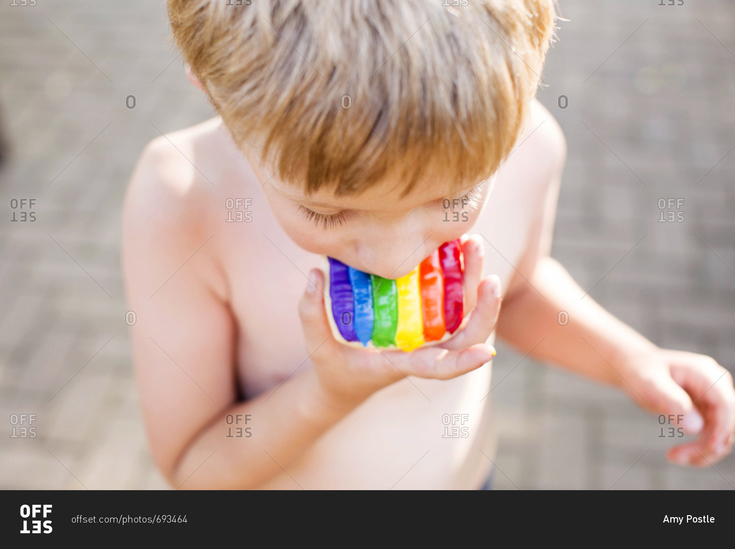 Overhead view of a child taking a bite of a rainbow cookie