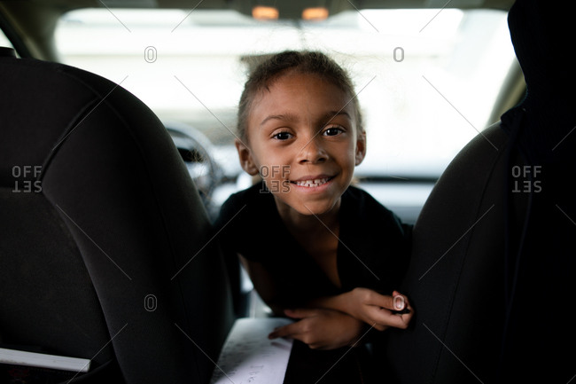 Little girl looking back from front seat of car