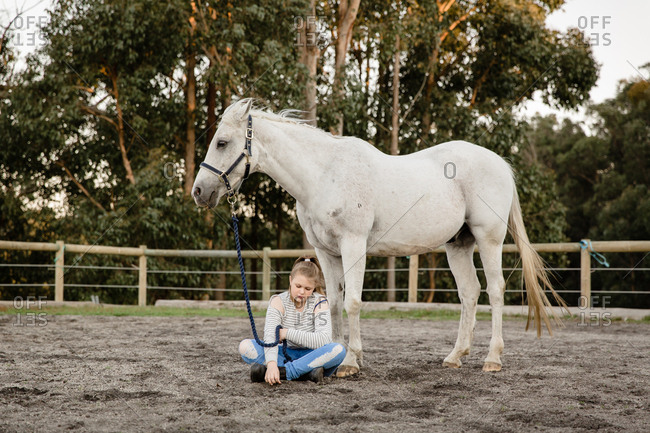 Girl sitting with horse in arena