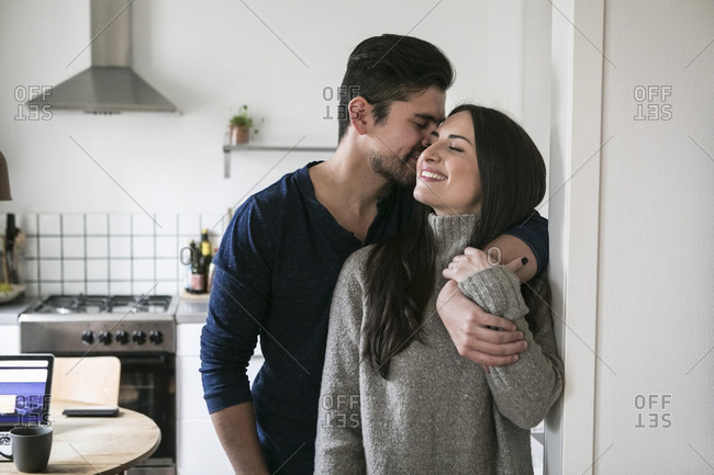Smiling couple romancing standing by wall at home