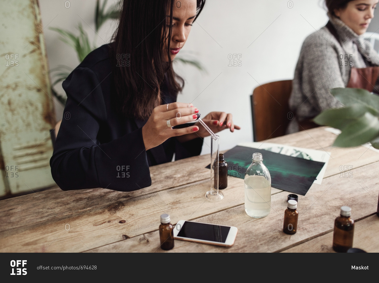 Mid adult woman mixing liquid with pipette in test tube at table in perfume workshop