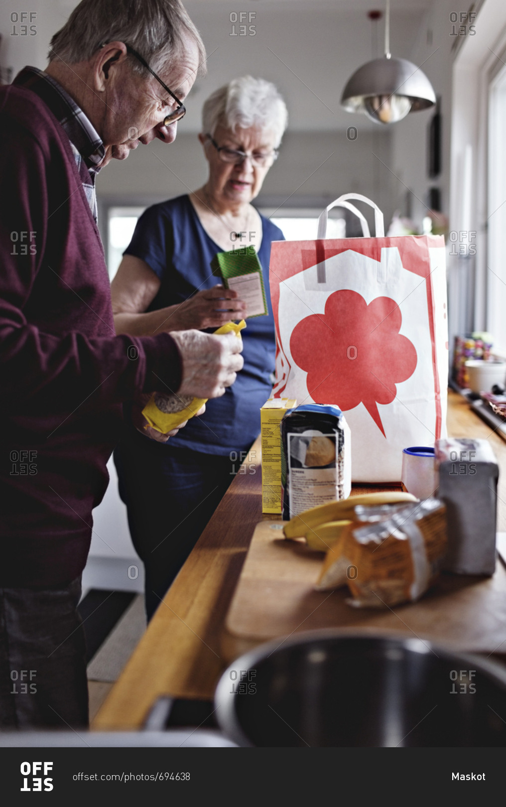 Retired senior couple with groceries on kitchen counter at home