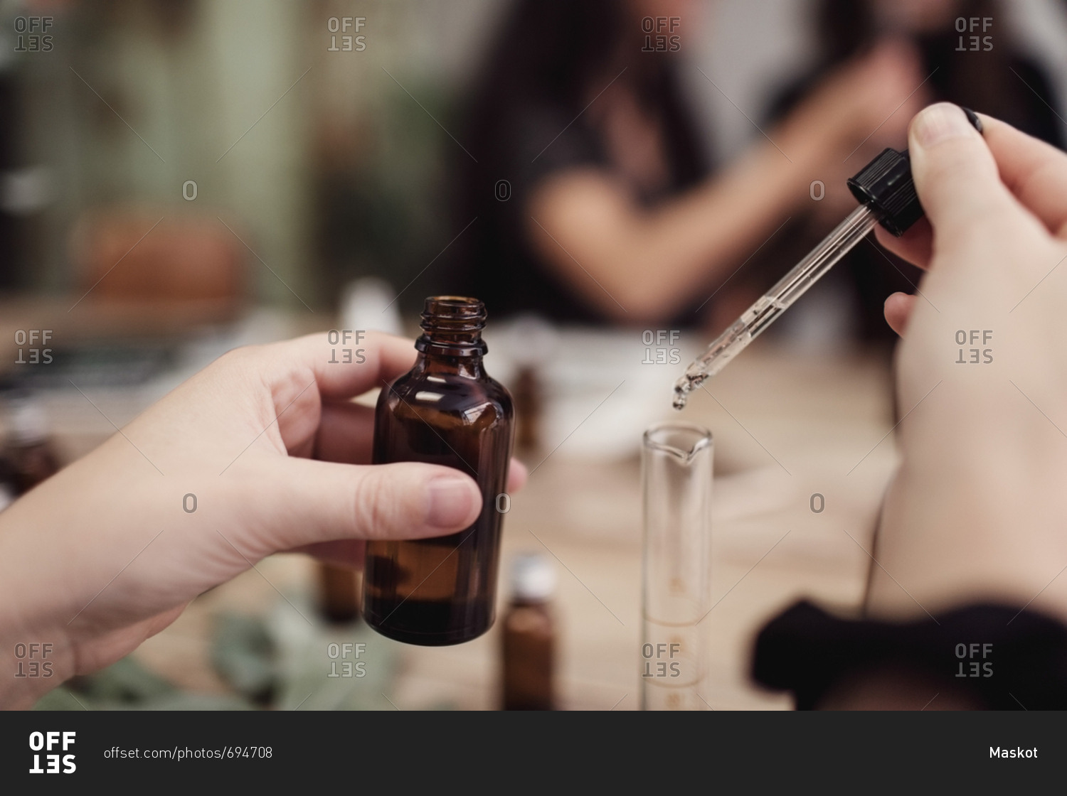Cropped hands of female owner mixing liquid in test tube from pipette at perfume workshop