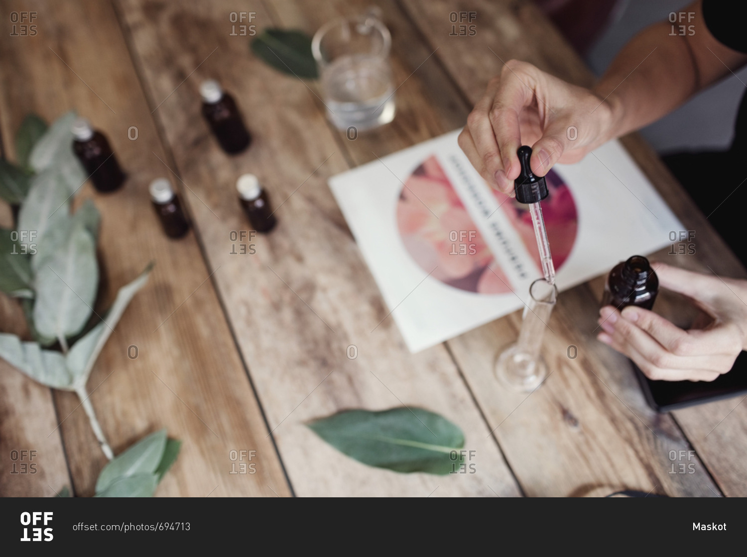 High angle view of woman using pipette for mixing liquid in test tube at perfume workshop