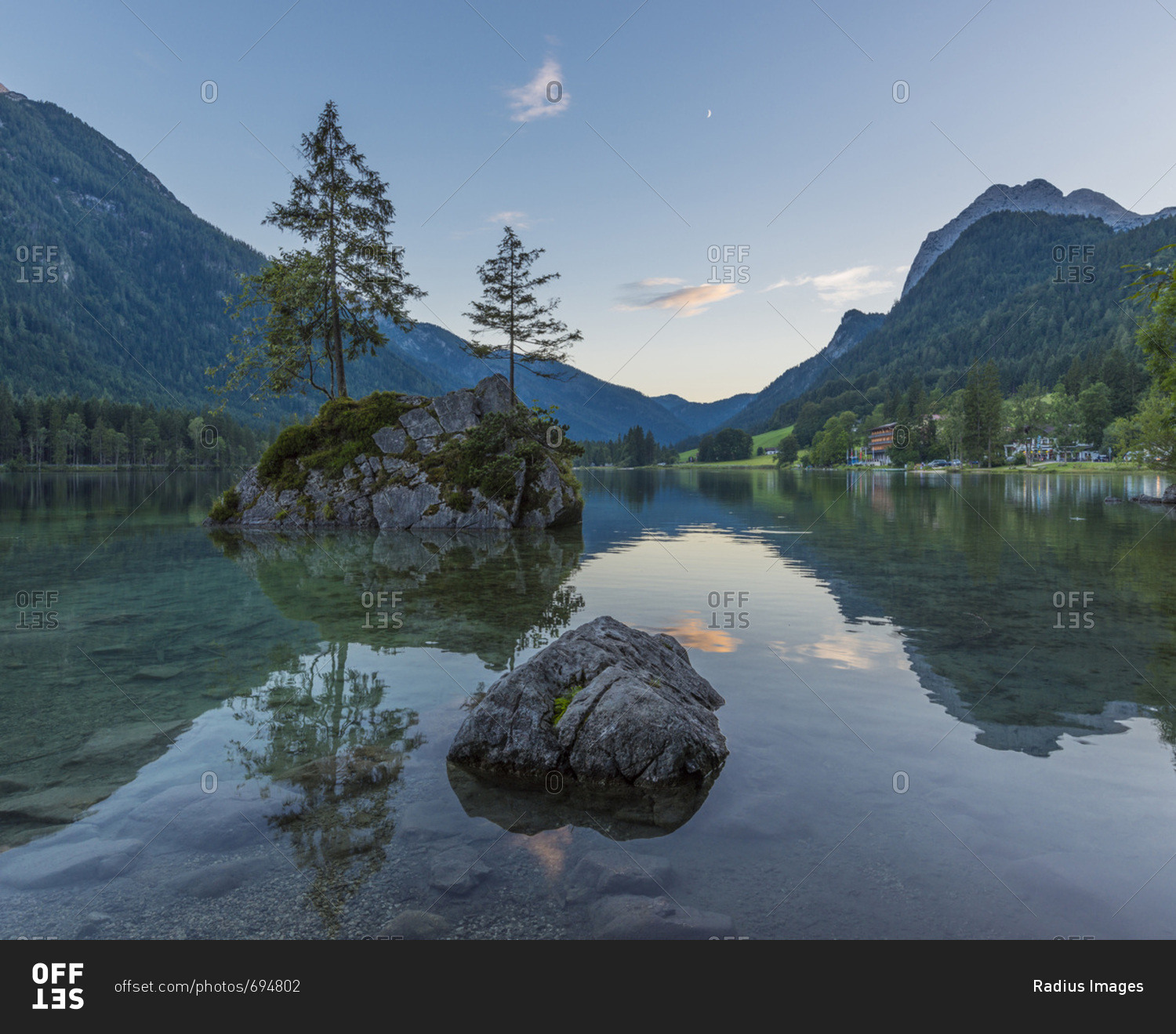 Lake Hintersee with mountains and trees growing on small, rock island at dawn at Ramsau in the Berchtesgaden National Park in Upper Bavaria, Bavaria, Germany