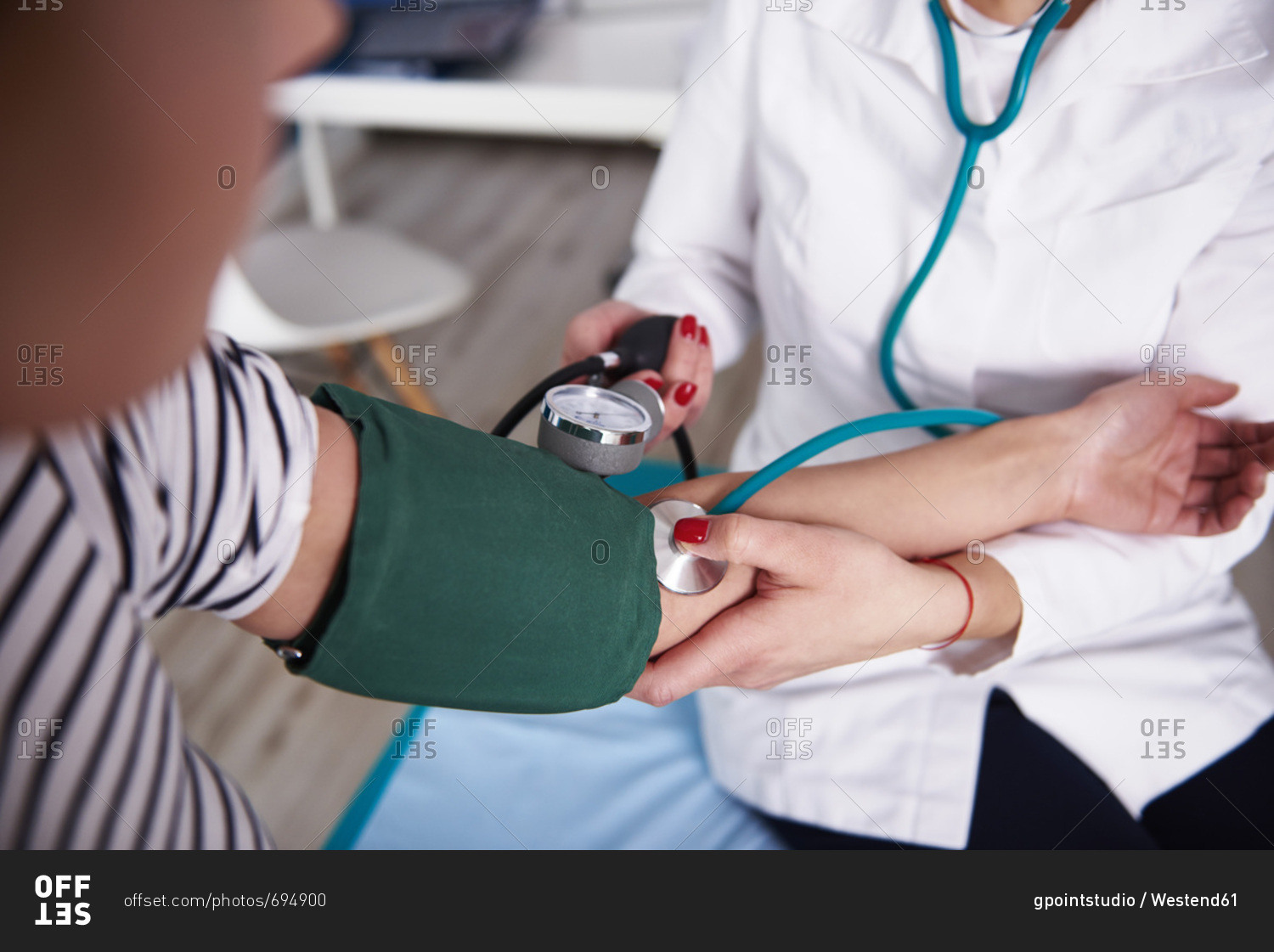 Doctor taking blood pressure of woman in medical practice stock photo