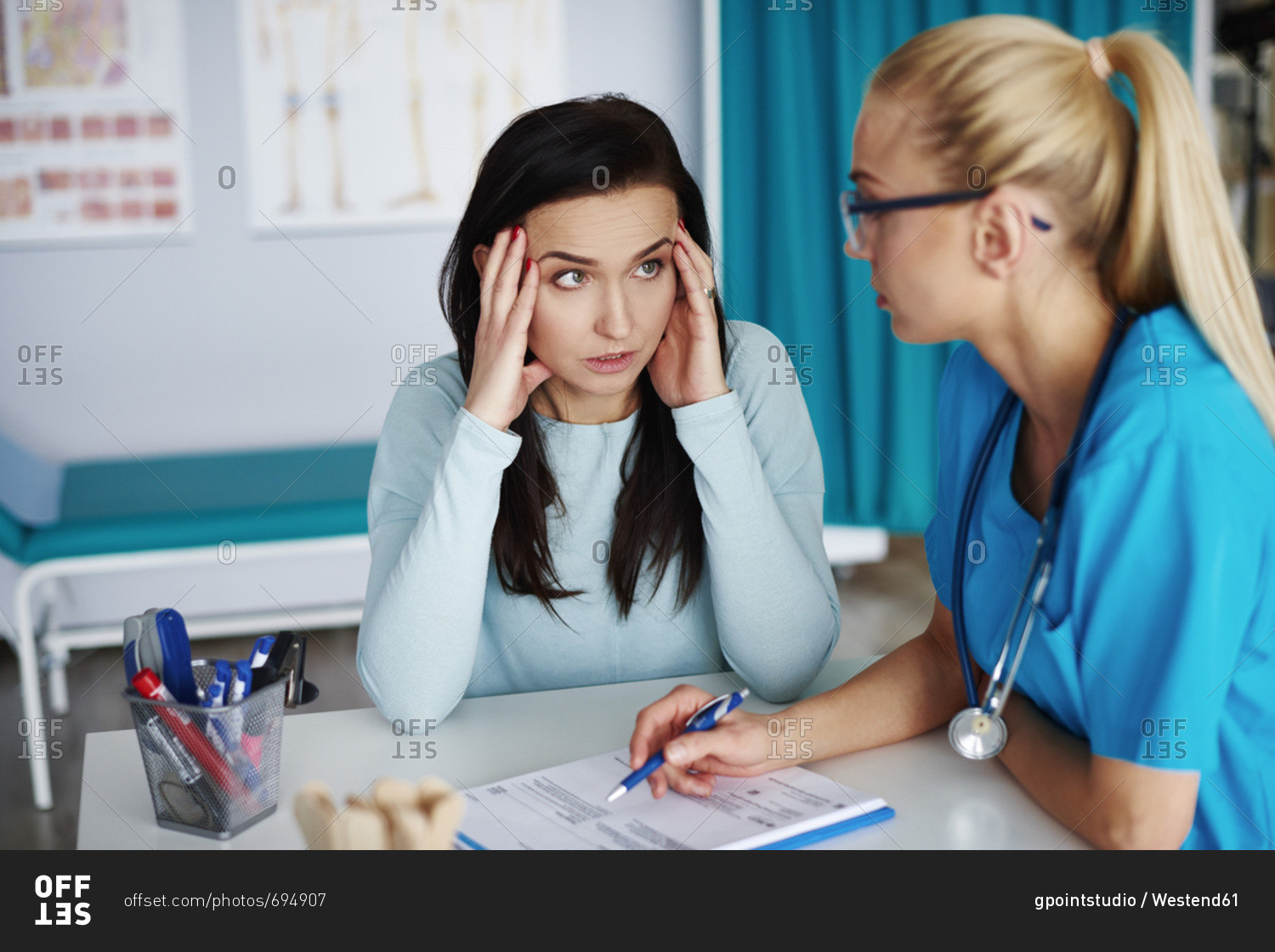 Worried woman talking to doctor in medical practice stock photo - OFFSET