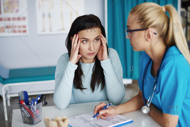 Worried woman talking to doctor in medical practice stock photo - OFFSET