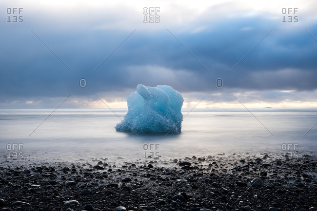 Solitary iceberg on rocky beach