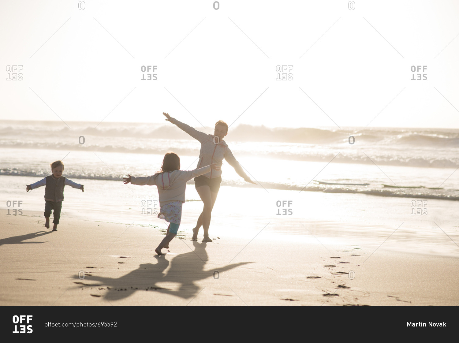 Little son and daughter having fun on the beach by the sea during sunset