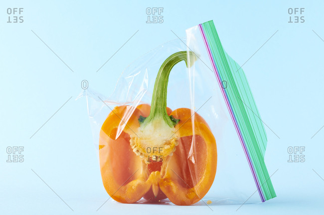 Raw bell pepper stored in clear plastic bag on solid color background