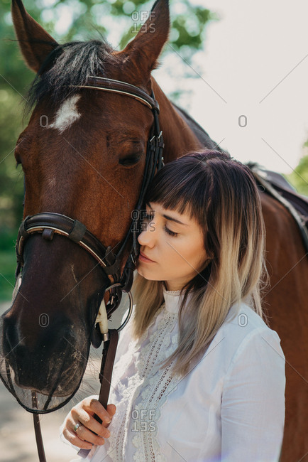 Portrait of woman in white summer dress next to her horse