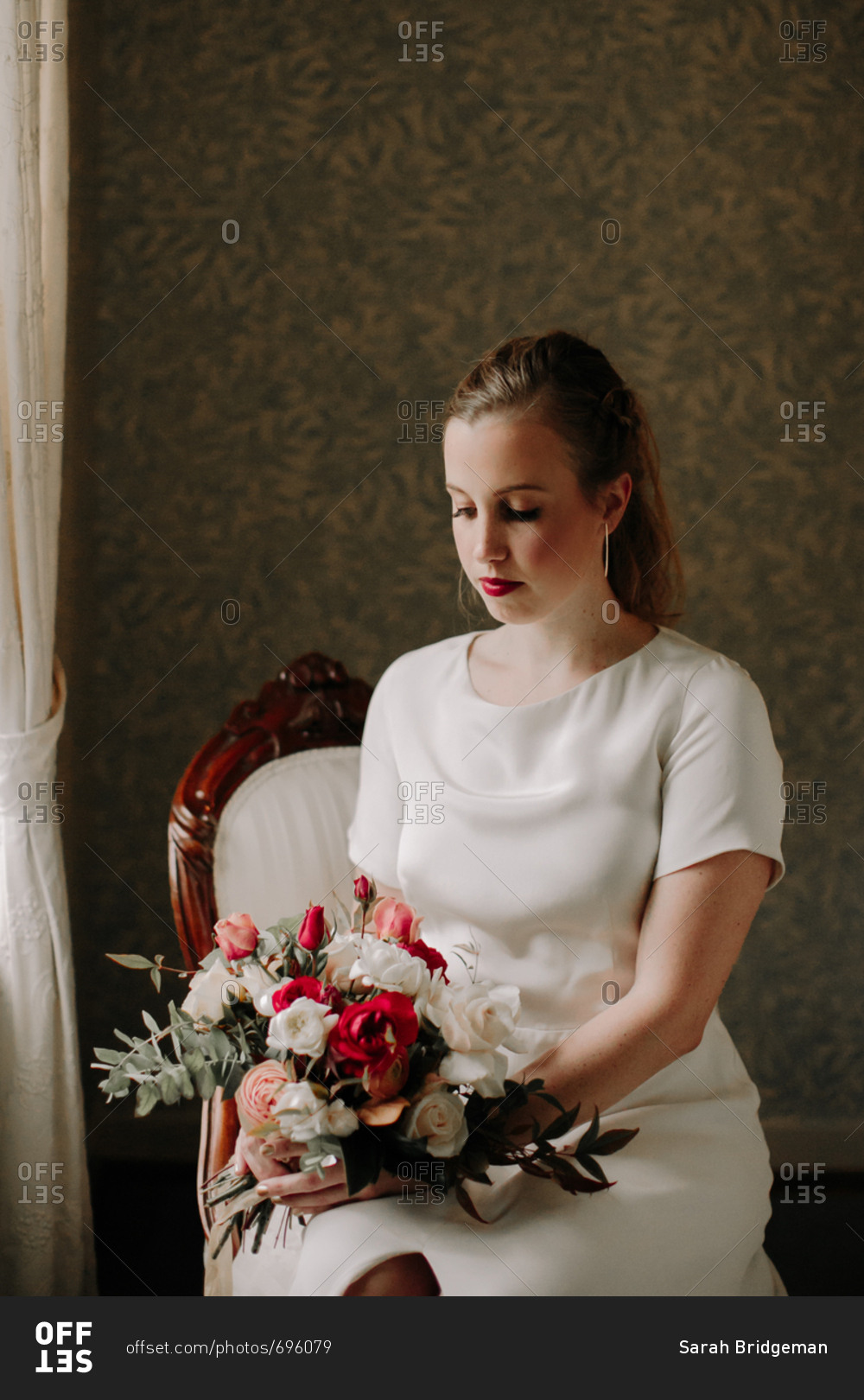Bride sitting on chair and holding wedding bouquet