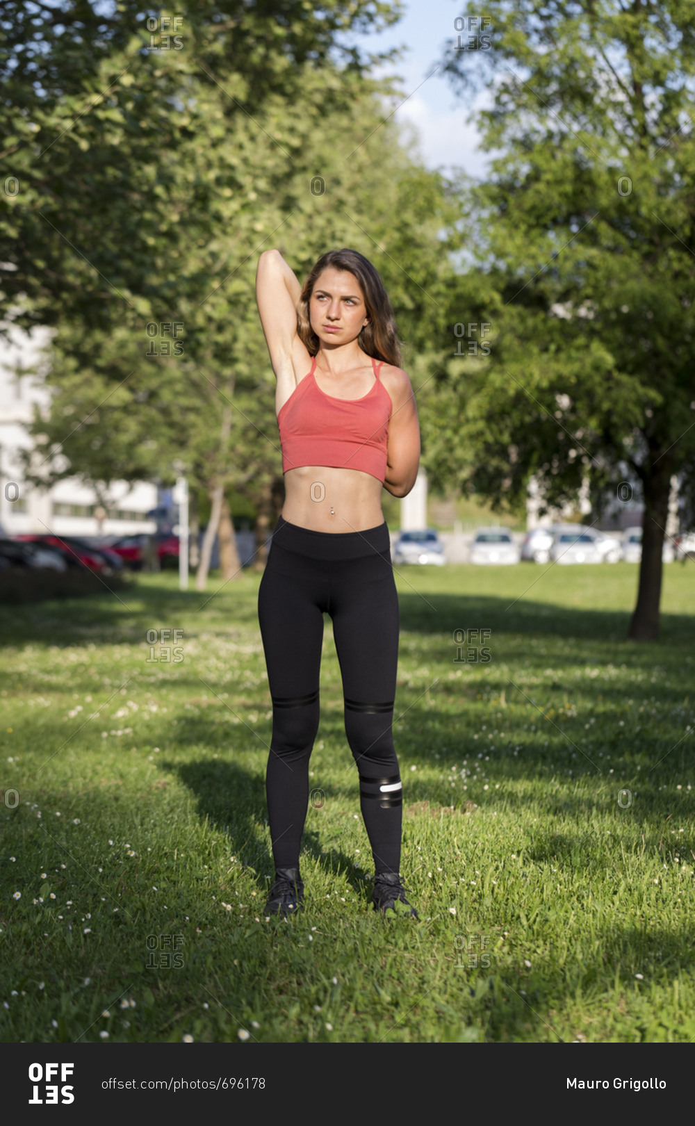 Young woman stretches her arms during an outdoor workout
