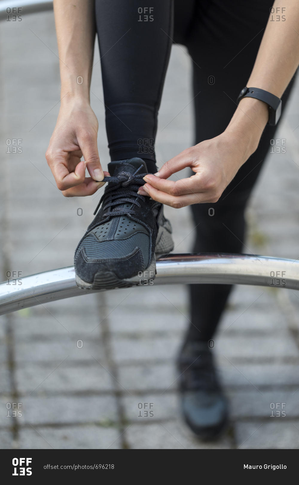 Young woman ties her athletic shoes during an outdoor workout