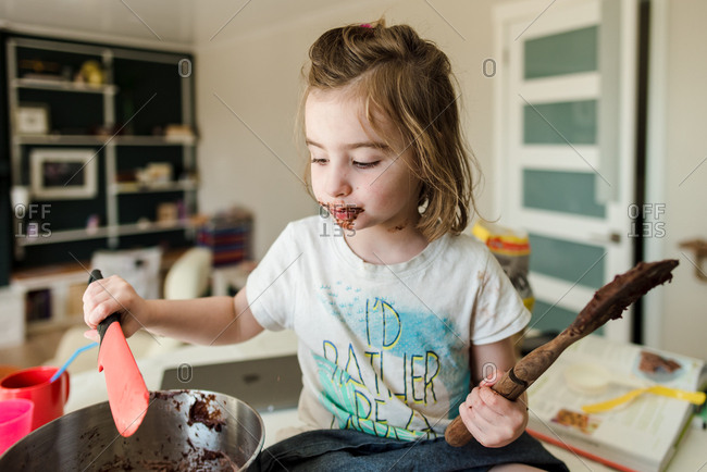 Young messy girl learning how to bake