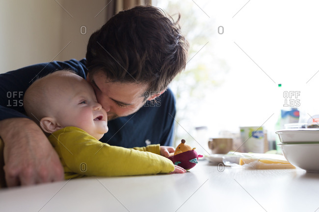 Young father playing with baby boy at breakfast table