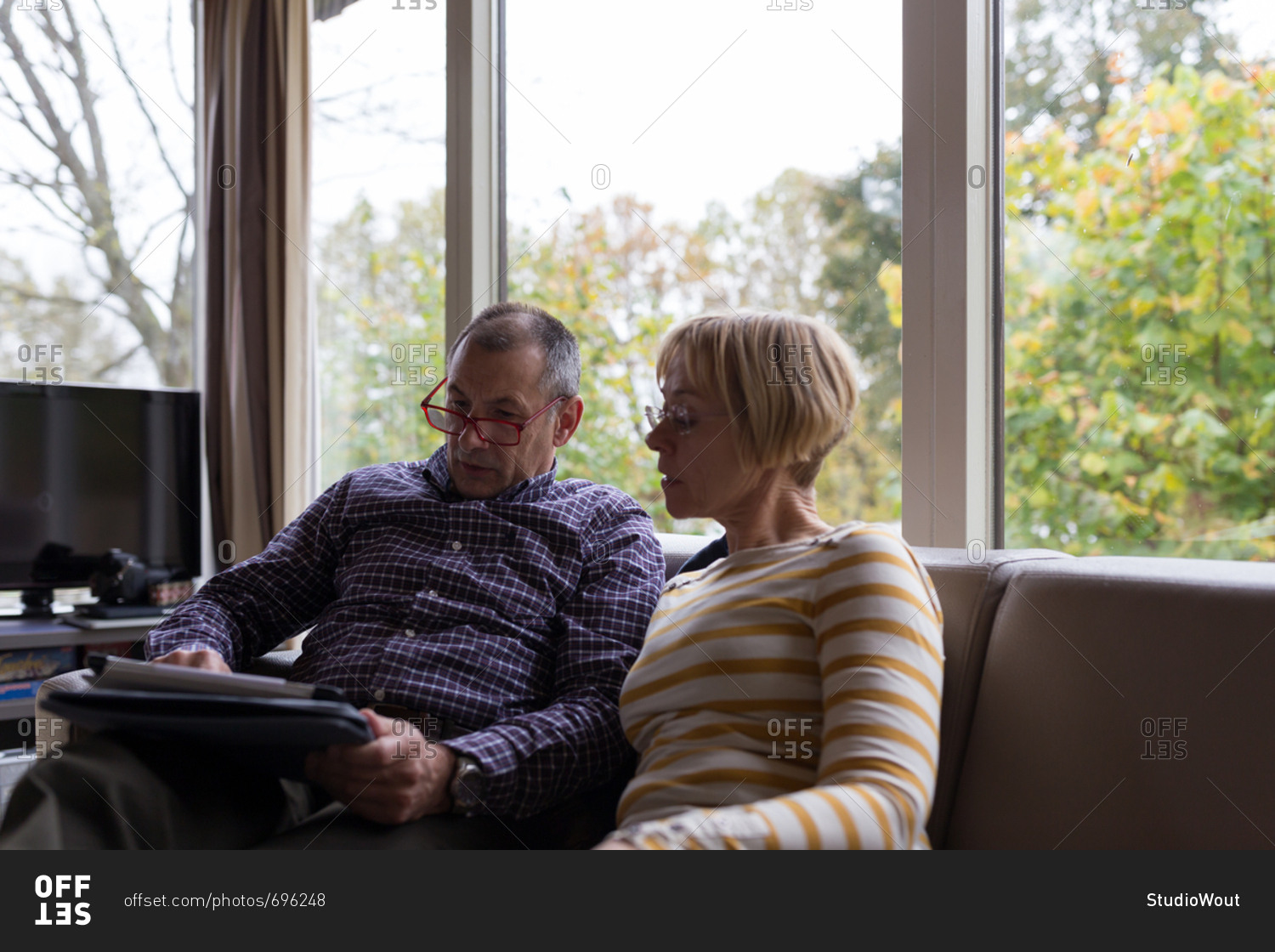 Senior couple looking at tablet computer together in homy sofa