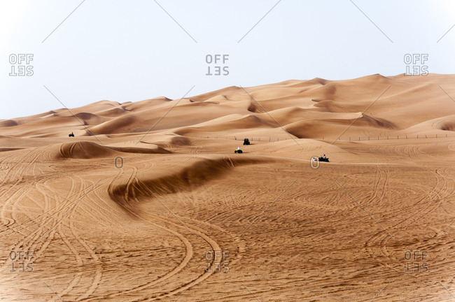 People riding all terrain vehicles in the sand dunes in the desert of Dubai, United Arab Emirates