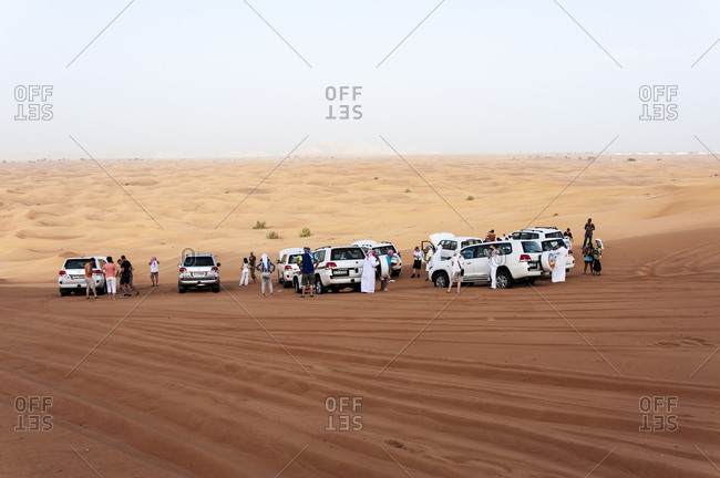 Dubai, United Arab Emirates - May 16, 2012: Tourists cluster around their vehicles while visiting the desert