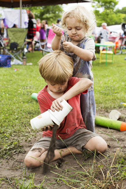 Two brothers playing in the dirt outside at a festival