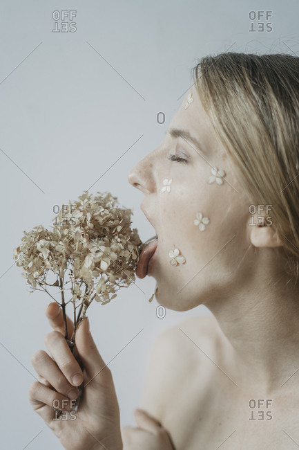 Profile of woman with flower petals on her face and tongue