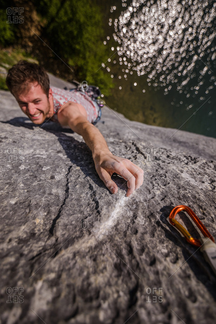 Young male rock climber reaching while climbing limestone rock face, Freyr, Belgium, high angle view