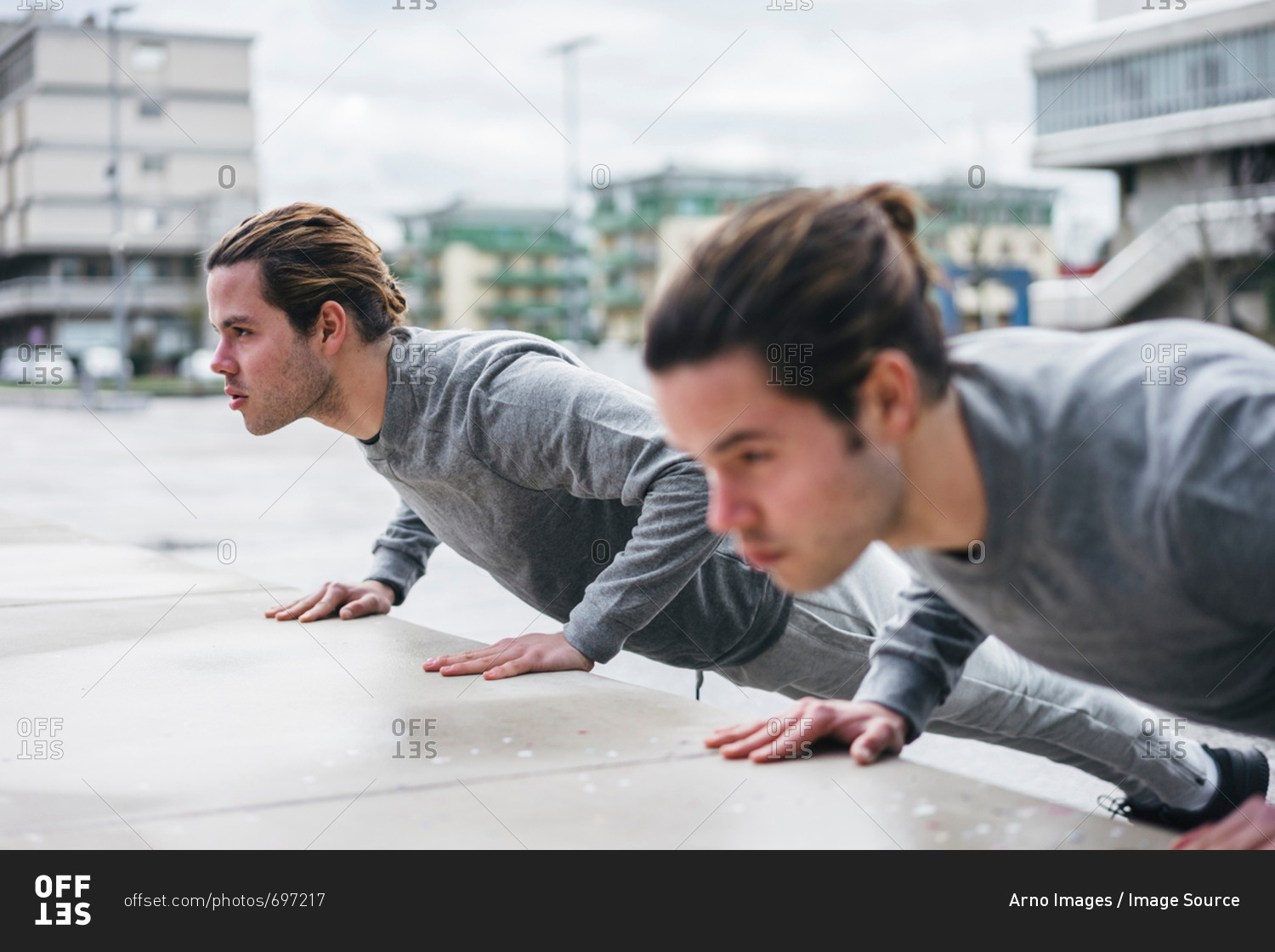 Young male twins doing push ups against wall in city